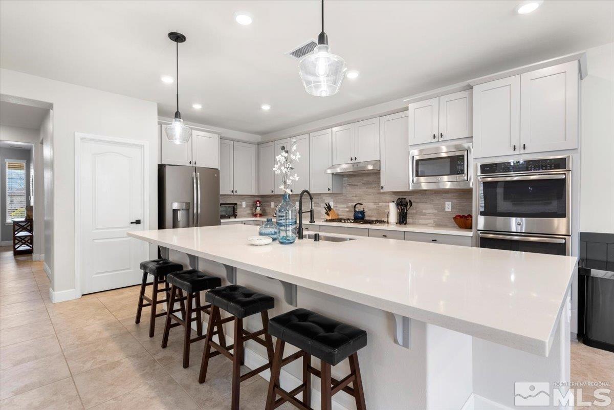 2711 McCauley Ranch Boulevard Reno, NV 89521 - Photo 12 of 40 a kitchen with stainless steel appliances a table chairs refrigerator and microwave