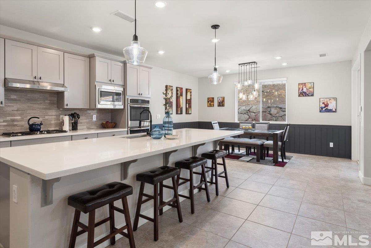 2711 McCauley Ranch Boulevard Reno, NV 89521 - Photo 13 of 40 a kitchen with stainless steel appliances kitchen island granite countertop a table chairs sink and cabinets