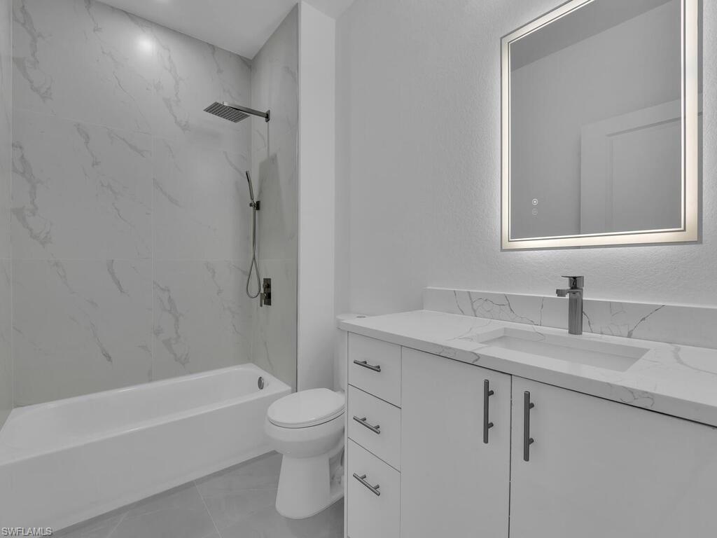 4450-4452 24th Street Southwest Lehigh Acres, FL 33973 - Photo 21 of 49 a bathroom with a granite countertop sink toilet and shower