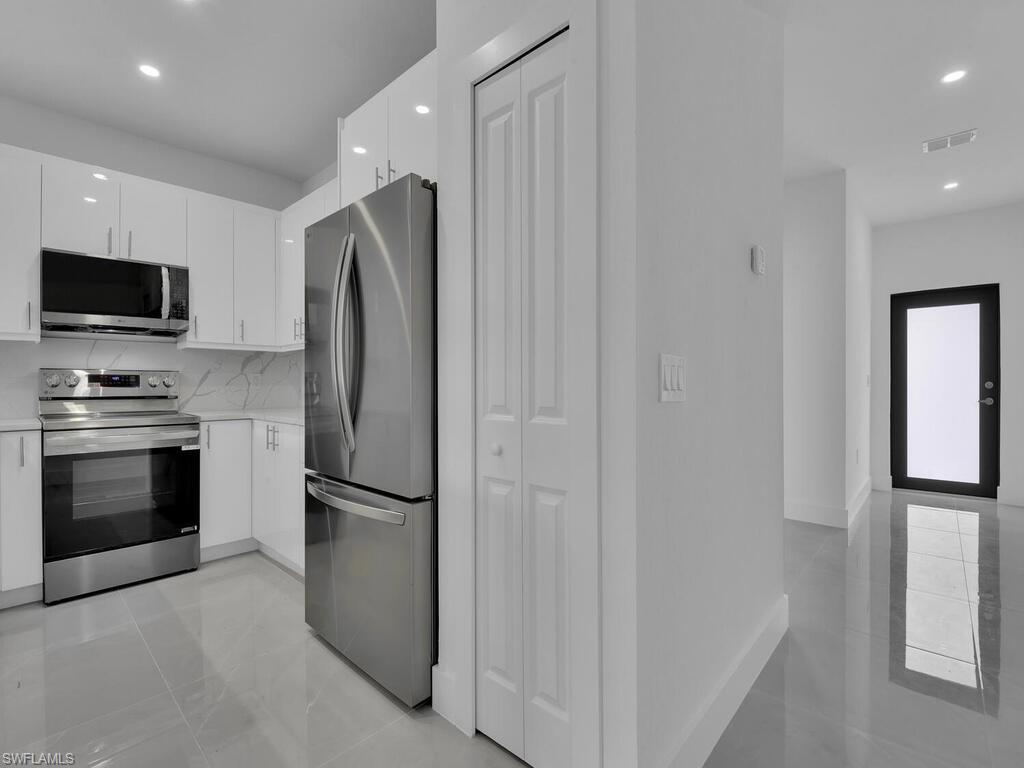 4450-4452 24th Street Southwest Lehigh Acres, FL 33973 - Photo 31 of 49 a kitchen with stainless steel appliances granite countertop a refrigerator and a stove top oven