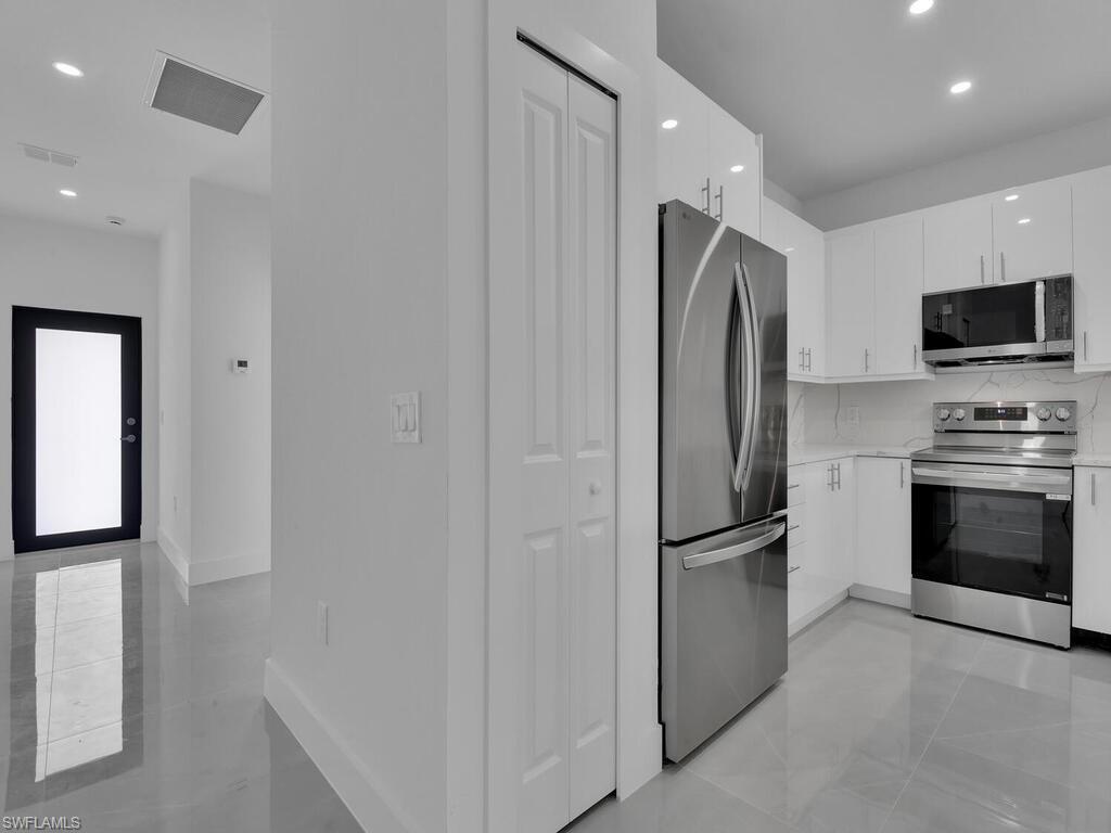 4450-4452 24th Street Southwest Lehigh Acres, FL 33973 - Photo 8 of 49 a kitchen with stainless steel appliances granite countertop a refrigerator and a stove top oven
