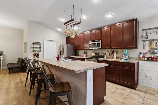 a kitchen with stainless steel appliances granite countertop a sink a stove a microwave a center island and chairs
