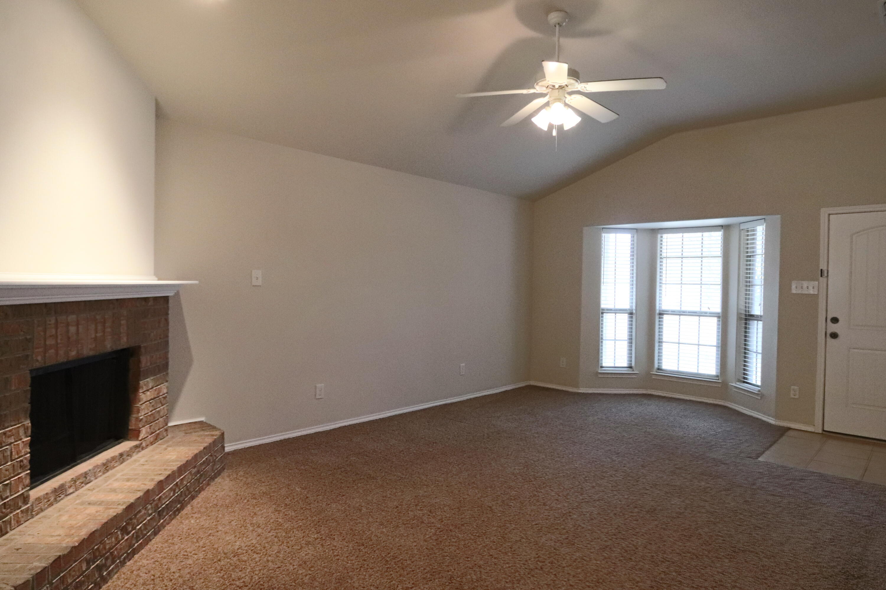 6810 83rd Street Lubbock, TX 79424 - Photo 2 of 9 a view of an empty room with chandelier fan and fire place