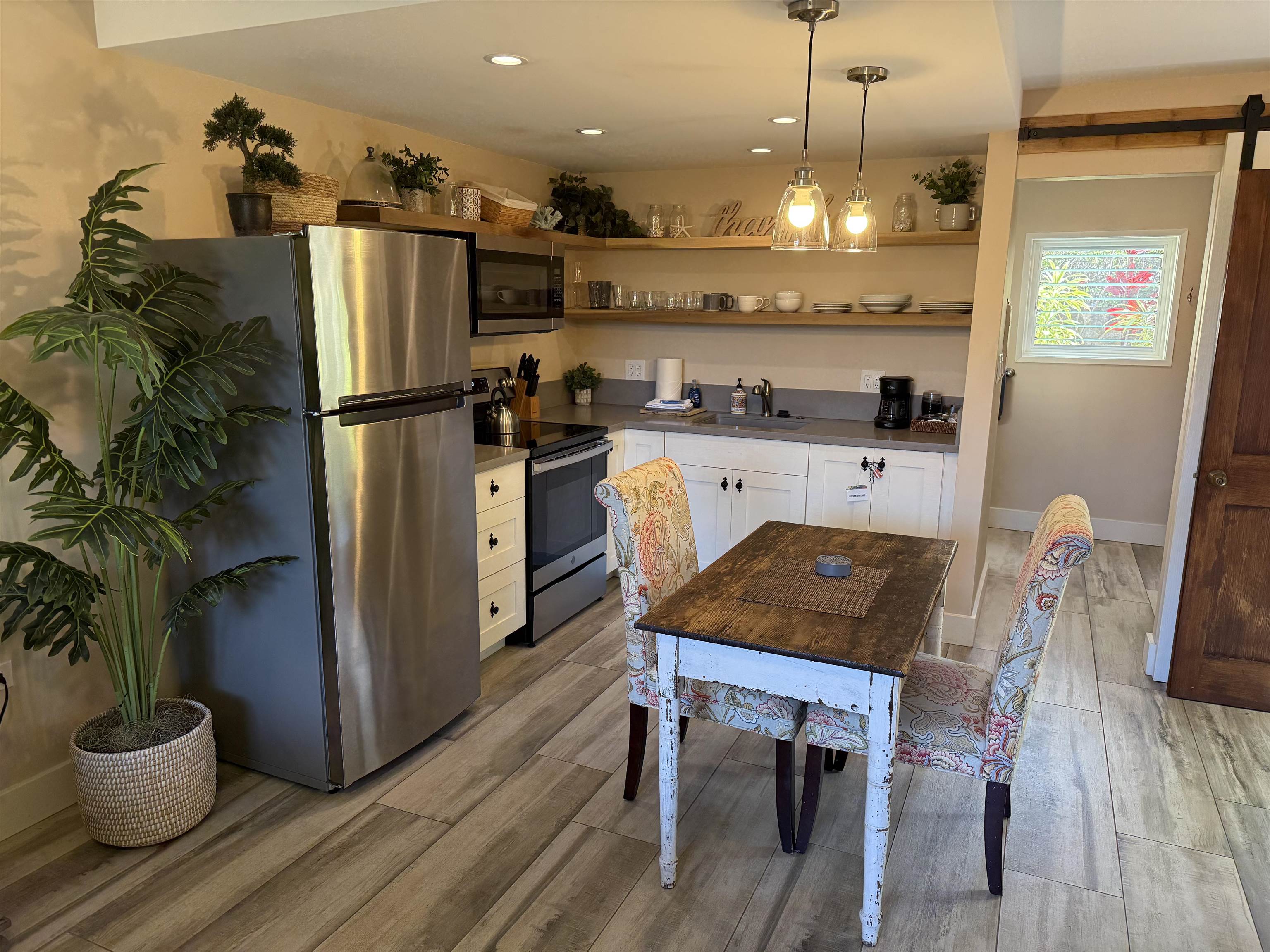 120 Hui F Road, Unit J1 Lahaina, HI 96761 - Photo 5 of 36 a kitchen with stainless steel appliances granite countertop a refrigerator a stove a sink dishwasher and a dining table with wooden floor