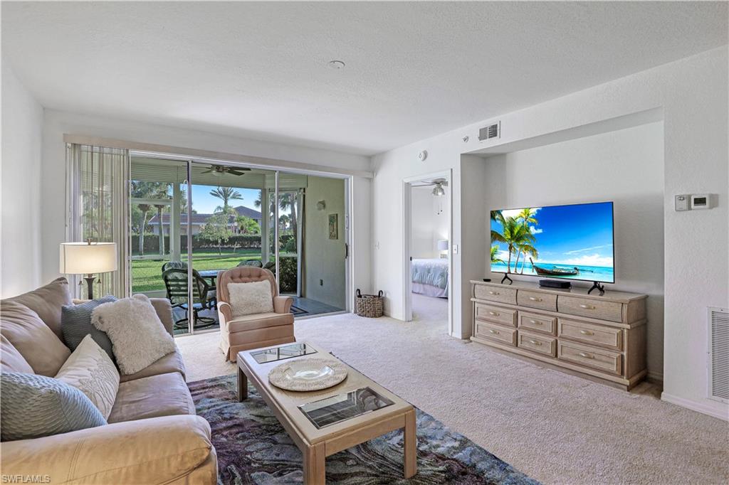 9022 Michael Circle, Unit 2205 Naples, FL 34113 - Photo 6 of 26 a living room with furniture a large window and a flat screen tv