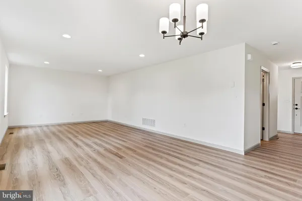 an empty room with wooden floor ceiling fan and windows
