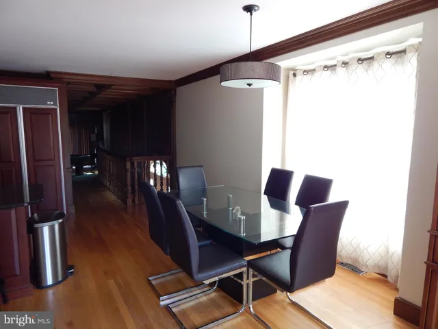 a dining room with furniture floor to ceiling window and wooden floor