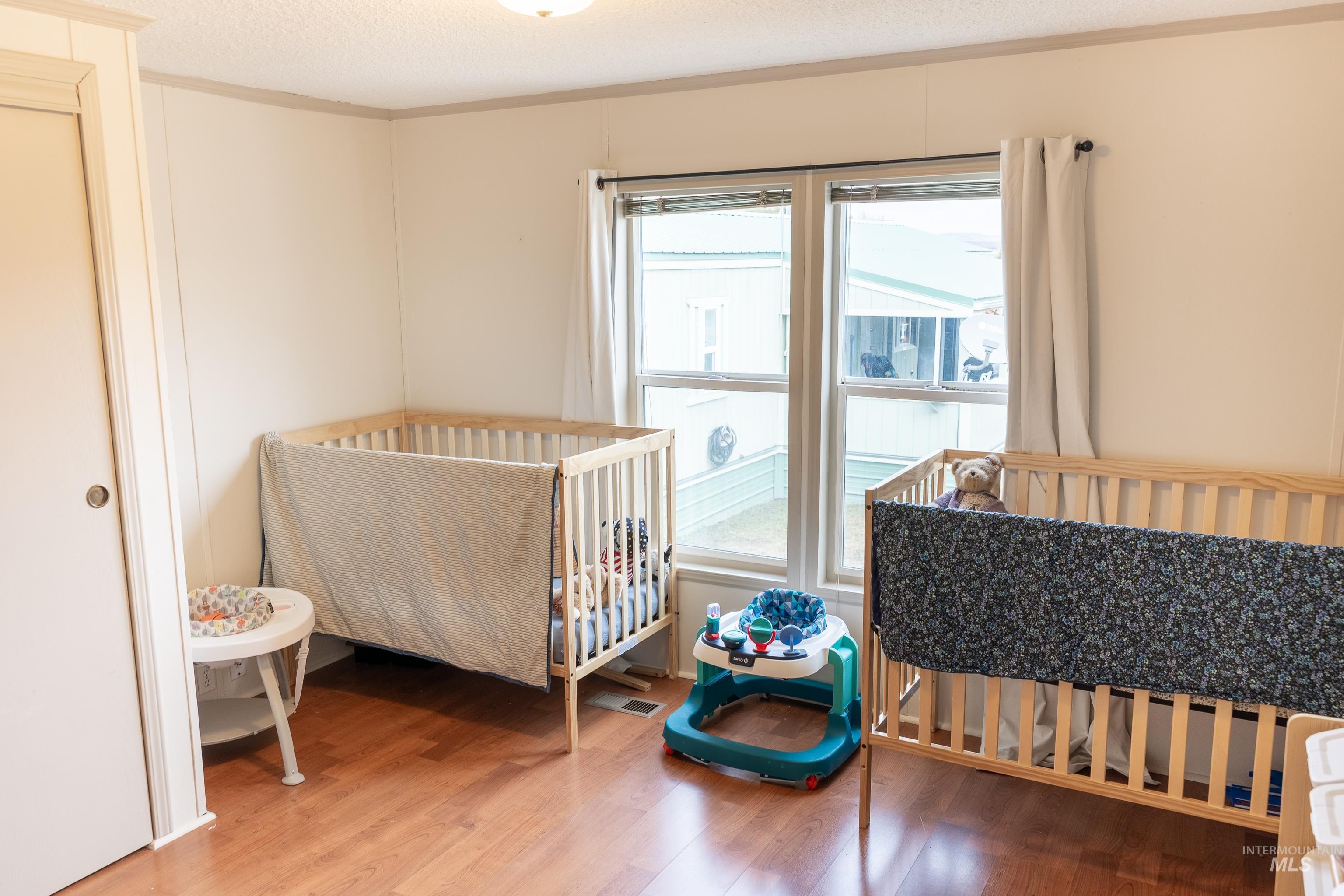 4325 Lenville Road, Unit 10 Moscow, ID 83843 - Photo 4 of 21 Bedroom featuring a crib, light wood finished floors, a textured ceiling, and ornamental molding