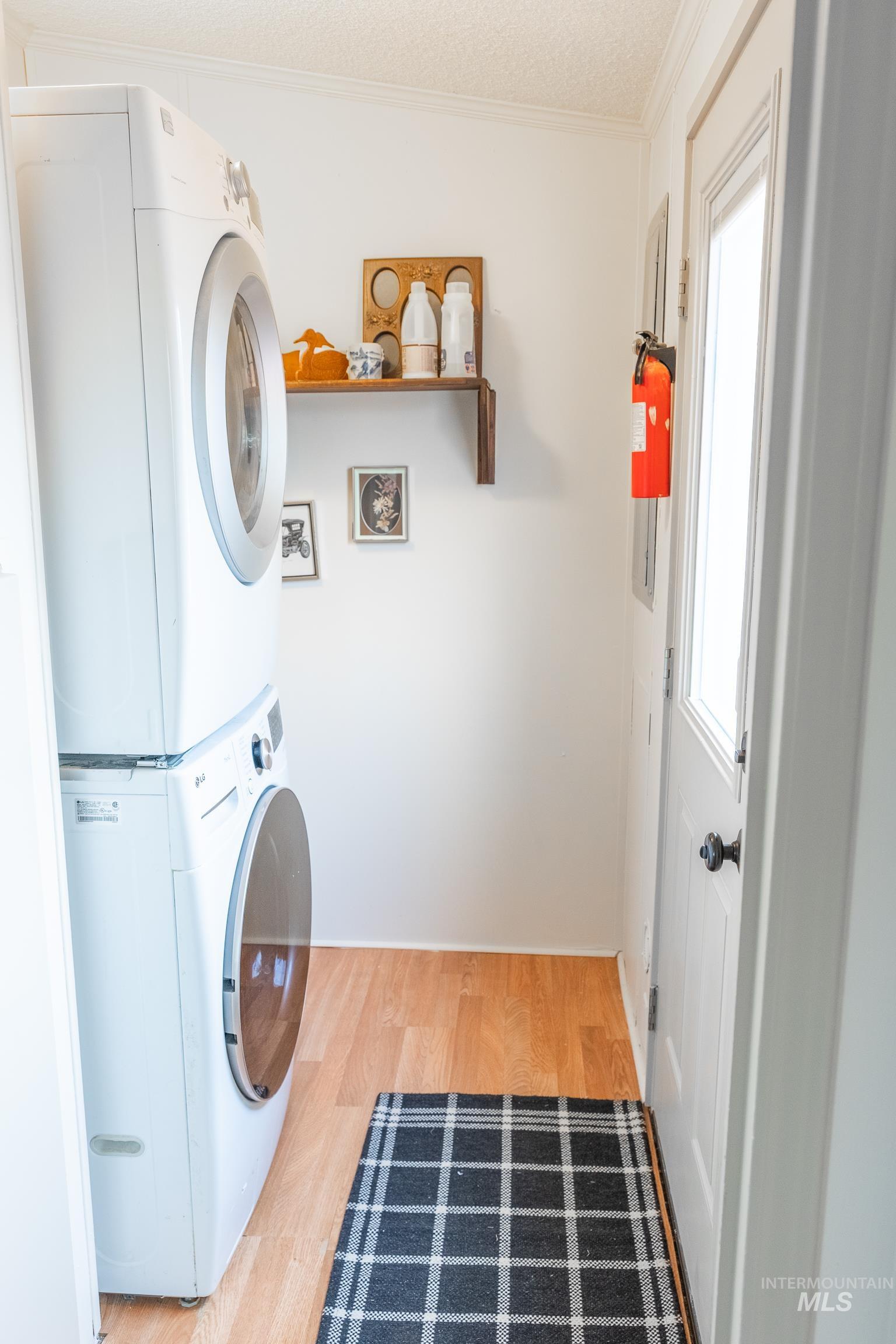 4325 Lenville Road, Unit 10 Moscow, ID 83843 - Photo 9 of 21 Washroom with ornamental molding, wood finished floors, stacked washer / drying machine, and a textured ceiling