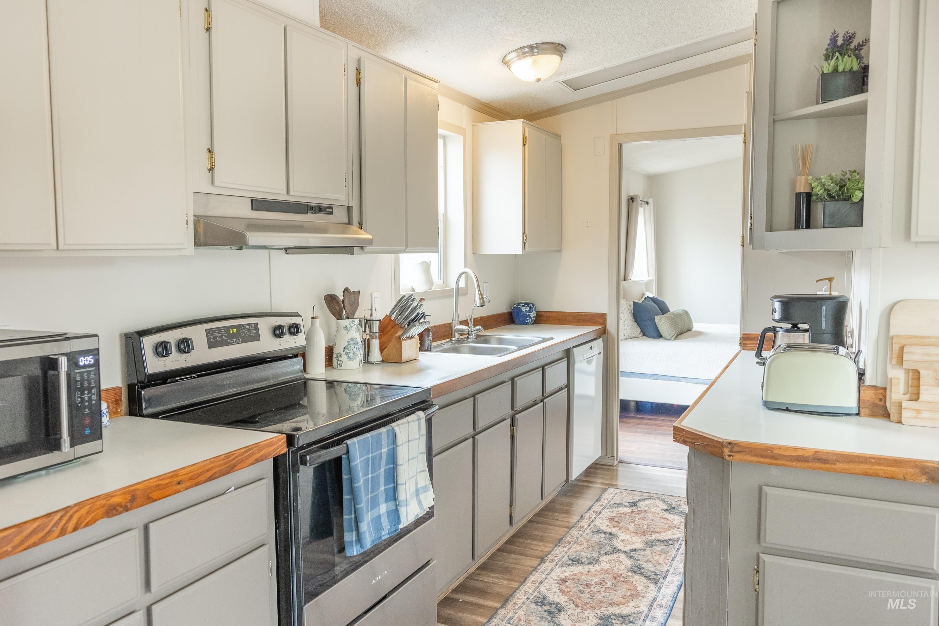 4325 Lenville Road, Unit 10 Moscow, ID 83843 - Photo 10 of 21 Kitchen featuring stainless steel appliances, light countertops, lofted ceiling, under cabinet range hood, and open shelves