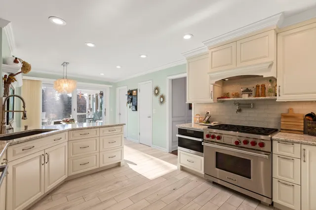 a kitchen with stainless steel appliances kitchen island granite countertop a dining table chairs and a refrigerator