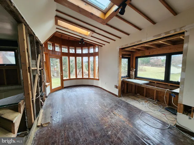 a view of an empty room with wooden floor and windows