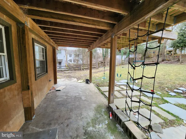 a backyard of a house with large trees and outdoor seating