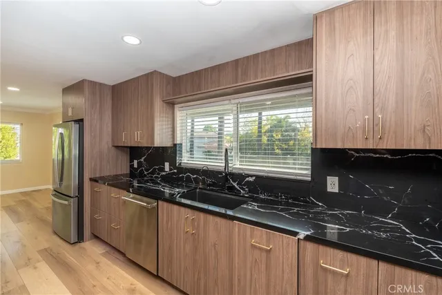 a kitchen with granite countertop a sink stainless steel appliances and cabinets