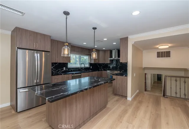 a kitchen with stainless steel appliances granite countertop a refrigerator a sink and a stove