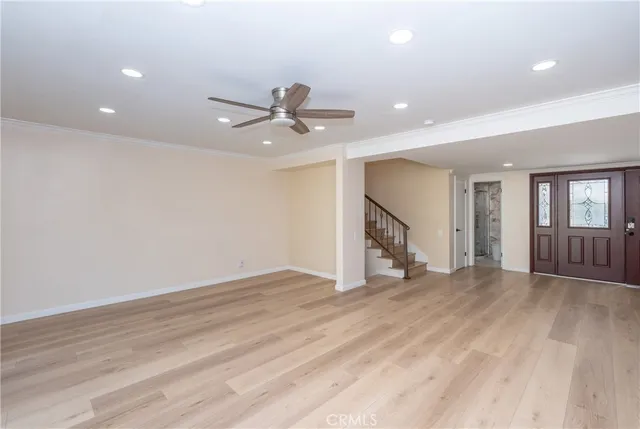 an empty room with wooden floor and a ceiling fan