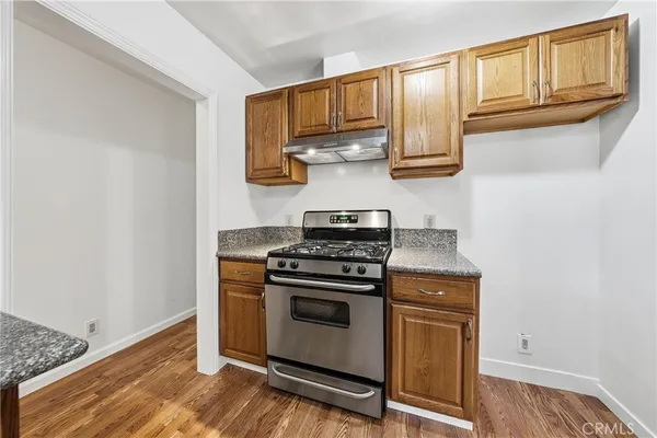 a kitchen with granite countertop wooden cabinets stainless steel appliances and a wooden floor