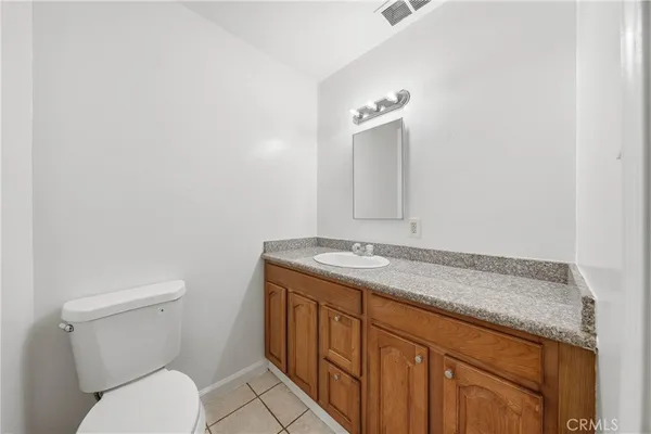 a bathroom with a granite countertop toilet sink and mirror