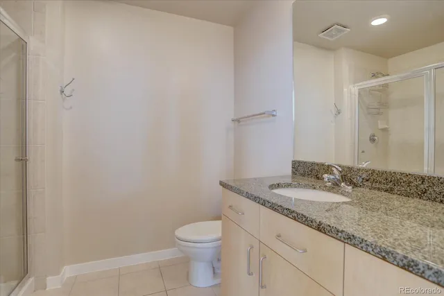 a bathroom with a granite countertop sink a toilet and a mirror