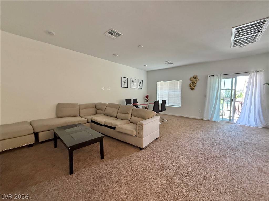 7777 South Westwind Road Las Vegas, NV 89139 - Photo 35 of 46 A spacious common area with plush carpet and abundant natural light from the balcony.