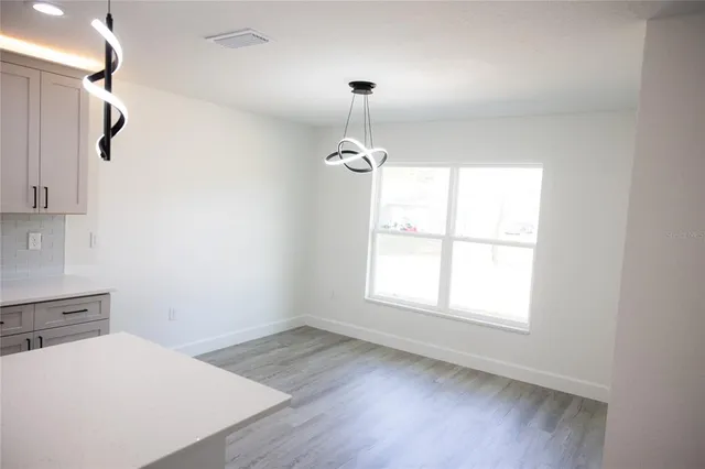 an empty room with wooden floor cabinet and windows