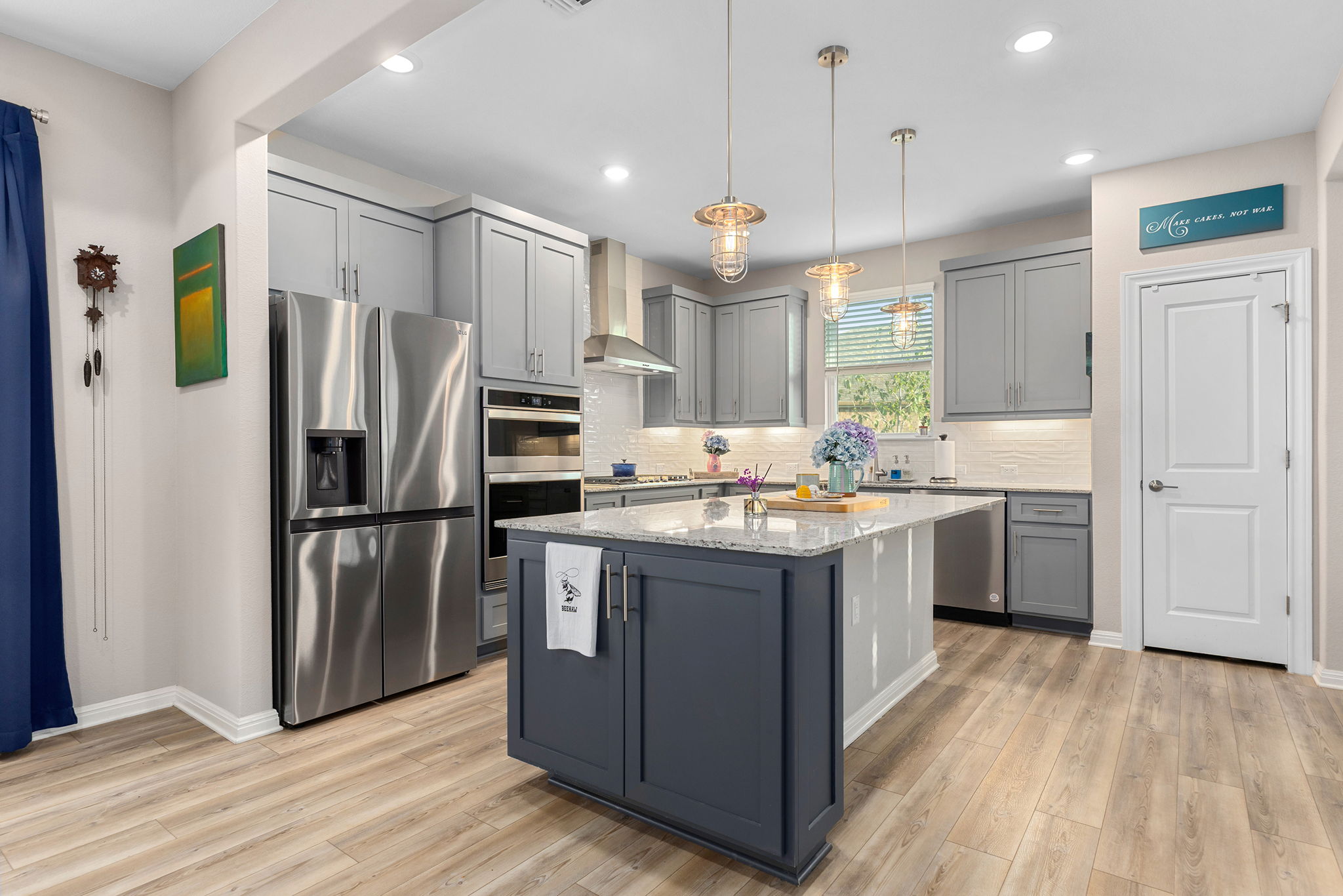 101 Bristol Cove Georgetown, TX 78633 - Photo 3 of 29 Kitchen featuring gray cabinetry, stainless steel appliances, hanging light fixtures, light stone countertops, and light wood-style floors
