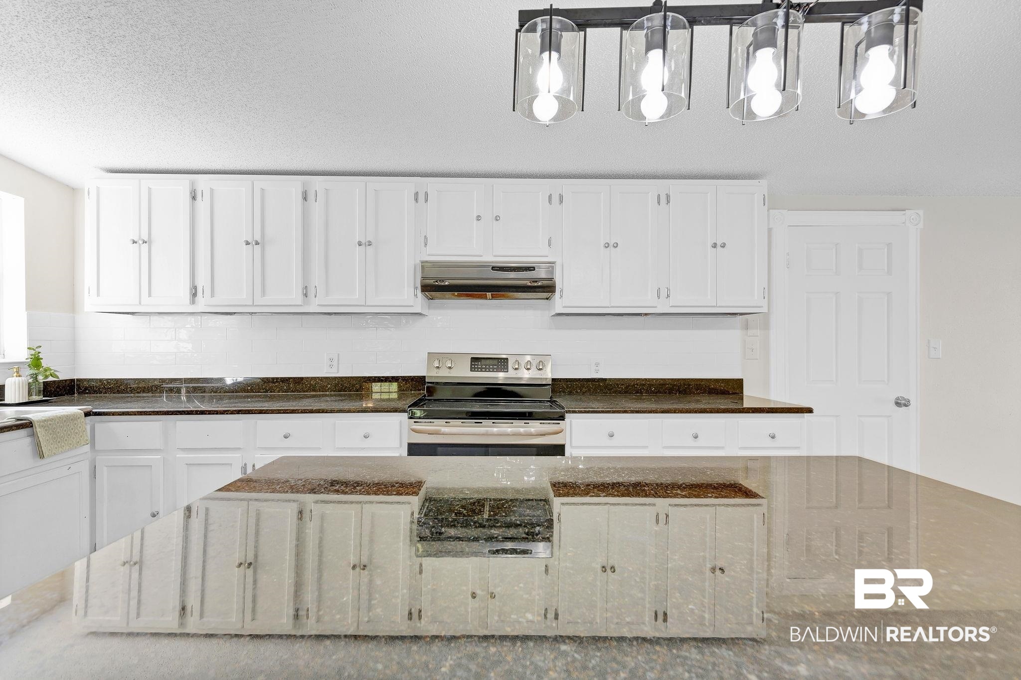11964 Stroh Road Daphne, AL 36527 - Photo 19 of 58 Kitchen with white cabinets, under cabinet range hood, stainless steel electric range oven, and dark stone counters