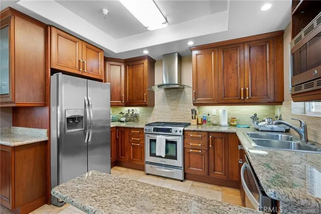 a kitchen with stainless steel appliances granite countertop a stove a sink dishwasher a refrigerator and cabinets with wooden floor