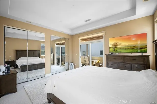 a large bedroom with a large bed and a flat tv screen on dresser