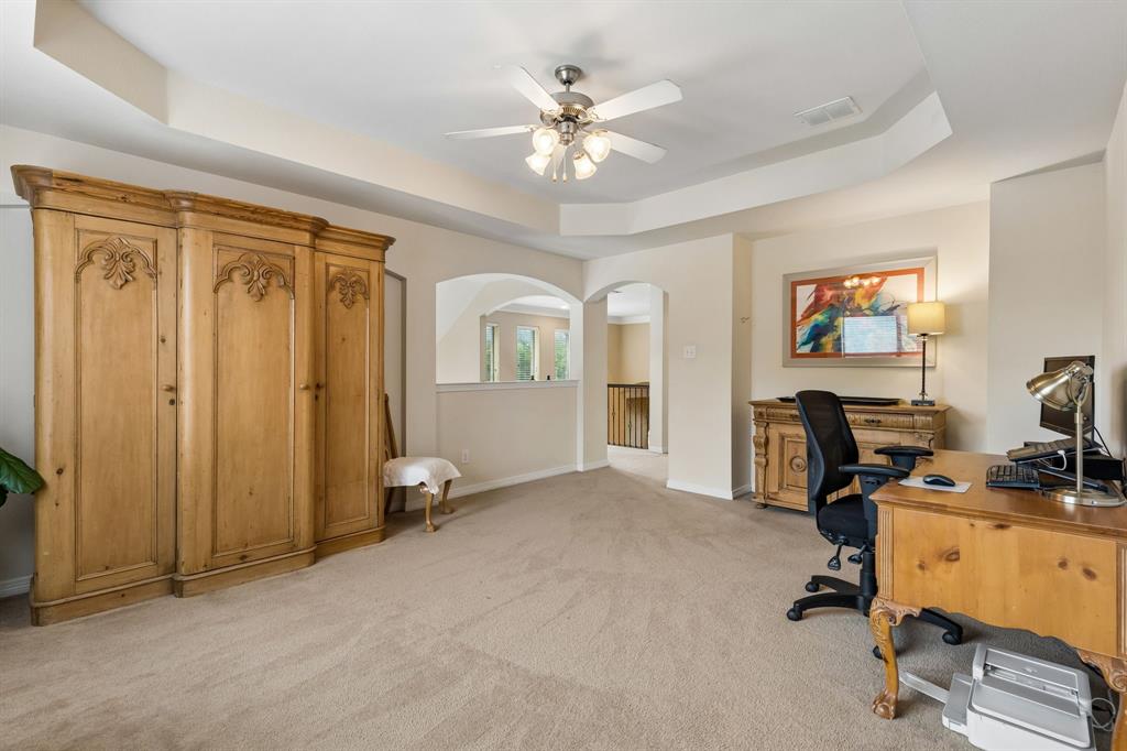 960 Remuda Road Frisco, TX 75033 - Photo 22 of 39 Spacious room featuring tray ceilings with a ceiling fan, neutral carpeting, and arched architectural details