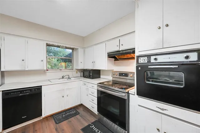 a kitchen with cabinets stainless steel appliances and wooden floor