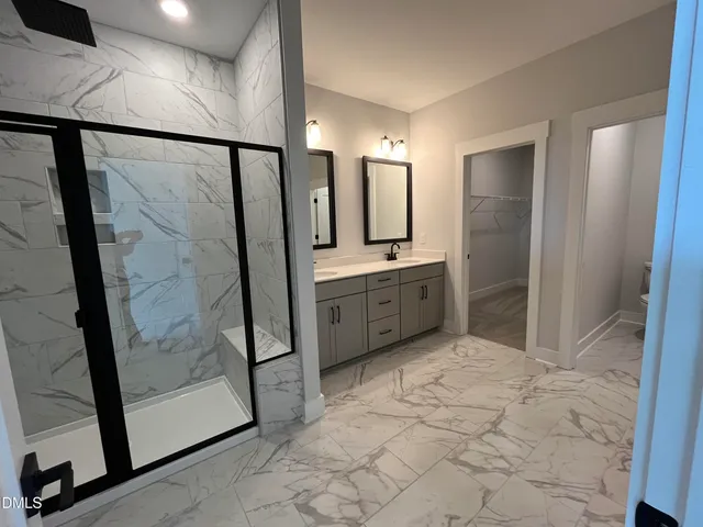 a bathroom with a double vanity sink and mirror with toilet