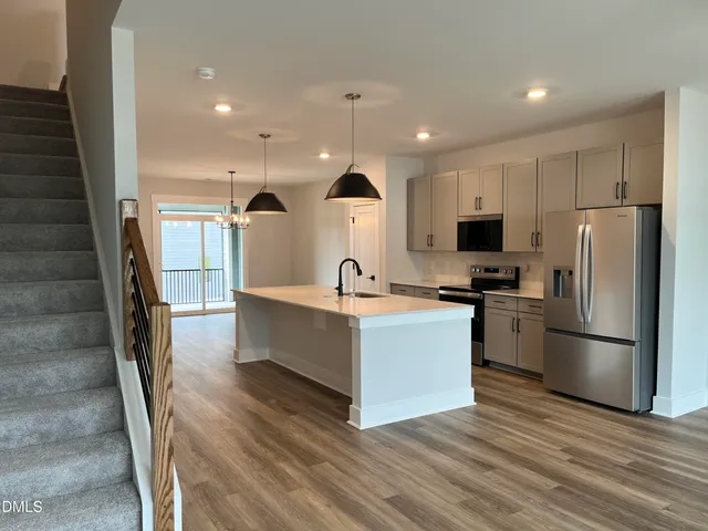 a kitchen with stainless steel appliances a stove a sink a refrigerator and a wooden floor