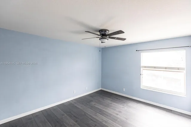 an empty room with a window and a fan