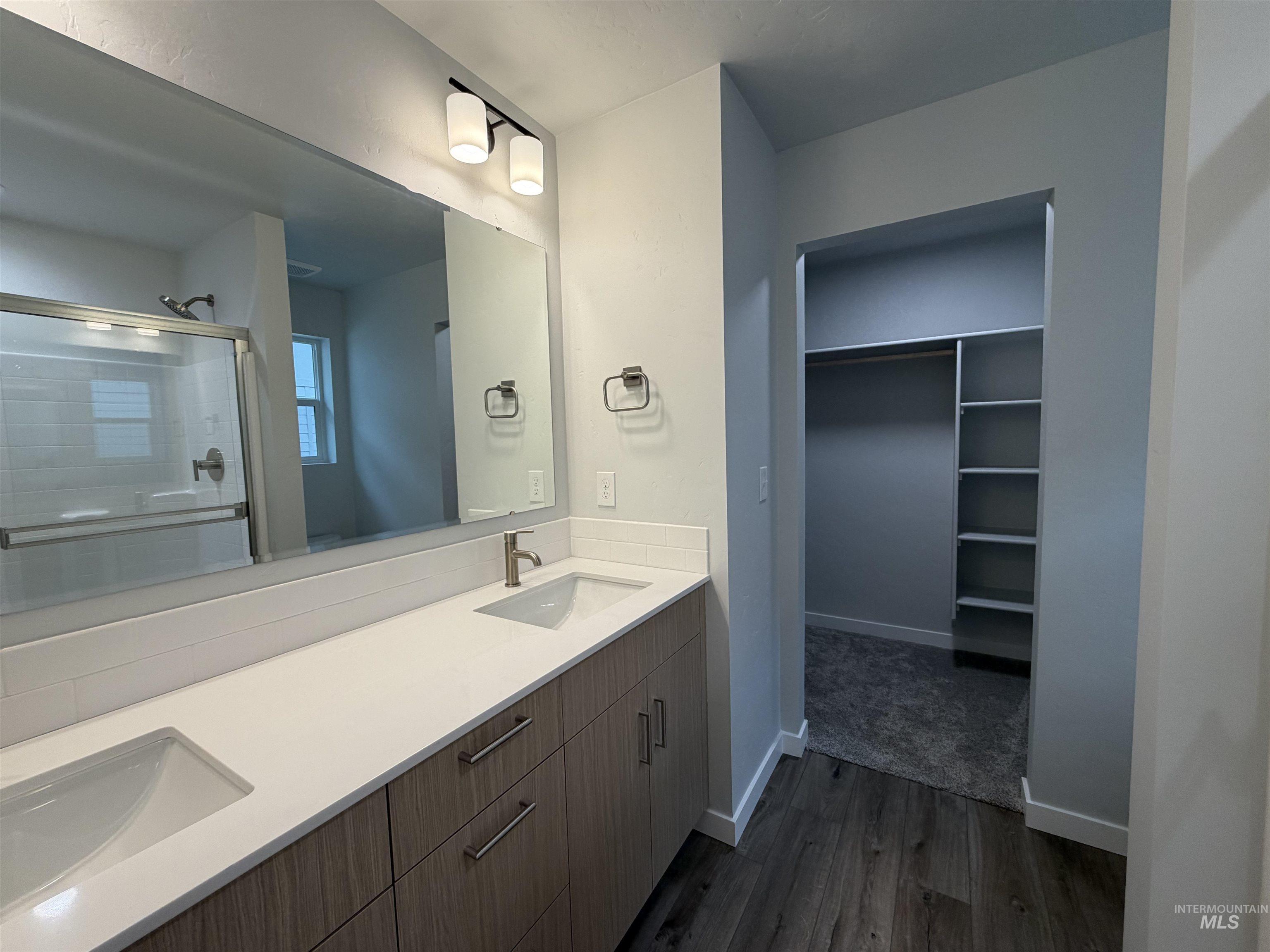 10550 West Tinder Street Star, ID 83669 - Photo 12 of 18 Full bathroom with a spacious closet, a stall shower, double vanity, and dark wood-style floors