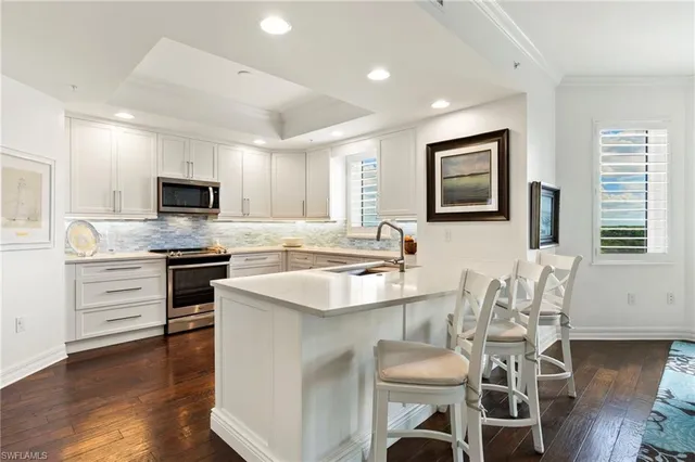 a kitchen with granite countertop white cabinets and stainless steel appliances