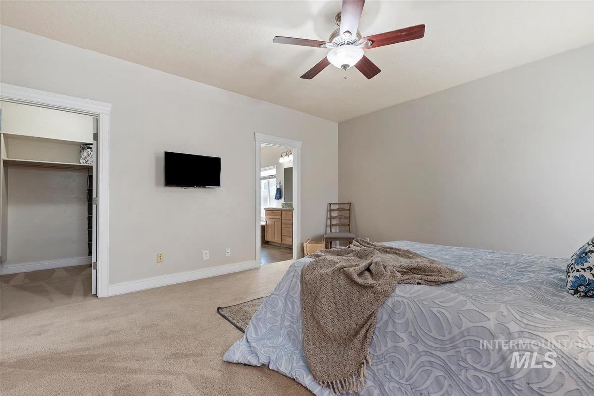 640 Southwest Miner Street Mountain Home, ID 83647 - Photo 19 of 35 Carpeted bedroom featuring a ceiling fan with light fixture, built-in shelving in the closet, and direct access to a bathroom with a dual vanity