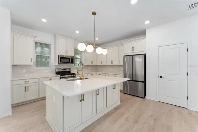 a large kitchen with kitchen island a sink stainless steel appliances and cabinets