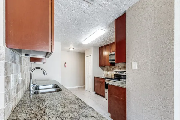 a kitchen with granite countertop a sink and a stove top oven