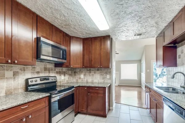 a kitchen with granite countertop stainless steel appliances a sink stove and cabinets