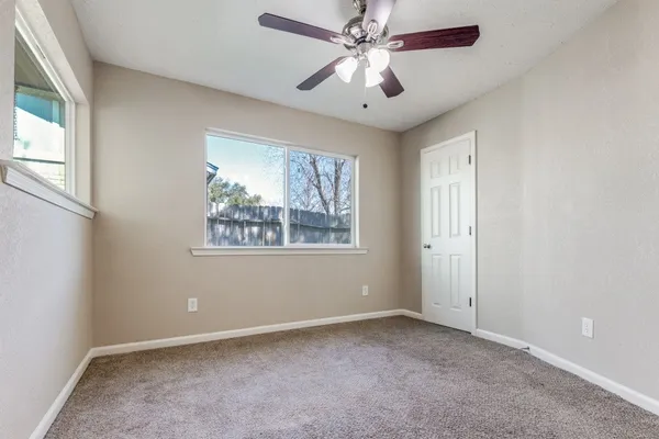 an empty room with a window and a fan