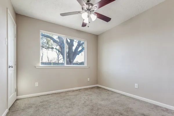 an empty room with windows and fan