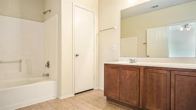 a bathroom with a tub sink shower and two mirror