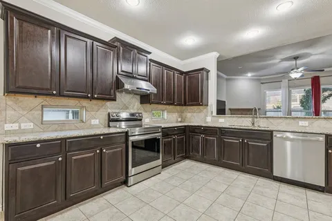 a kitchen with stainless steel appliances granite countertop wooden cabinets a sink and dishwasher a stove top oven