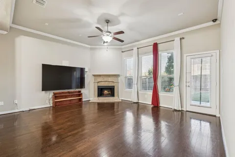 a view of an empty room with wooden floor fireplace and a window