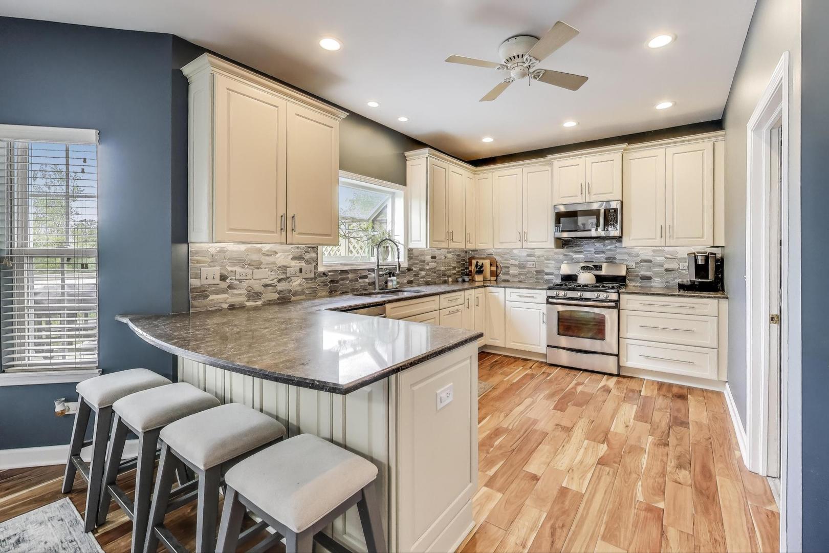 17119 West Prairieview Lane Gurnee, IL 60031 - Photo 7 of 40 a kitchen with kitchen island granite countertop a stove a sink a microwave and dining table