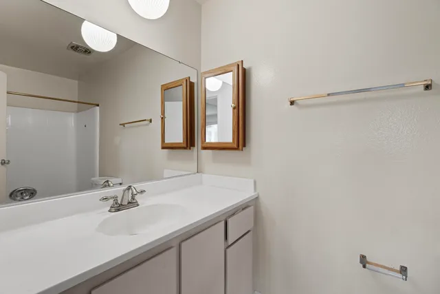 a bathroom with a sink a toilet a mirror and shower