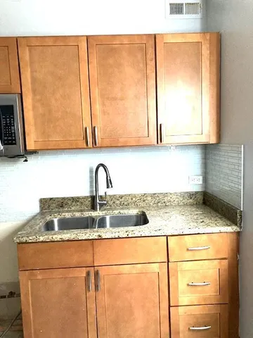 a kitchen with granite countertop sink and cabinets