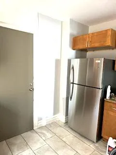 a view of a refrigerator in kitchen and an empty room