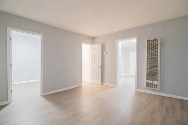 a view of an empty room with wooden floor and closet